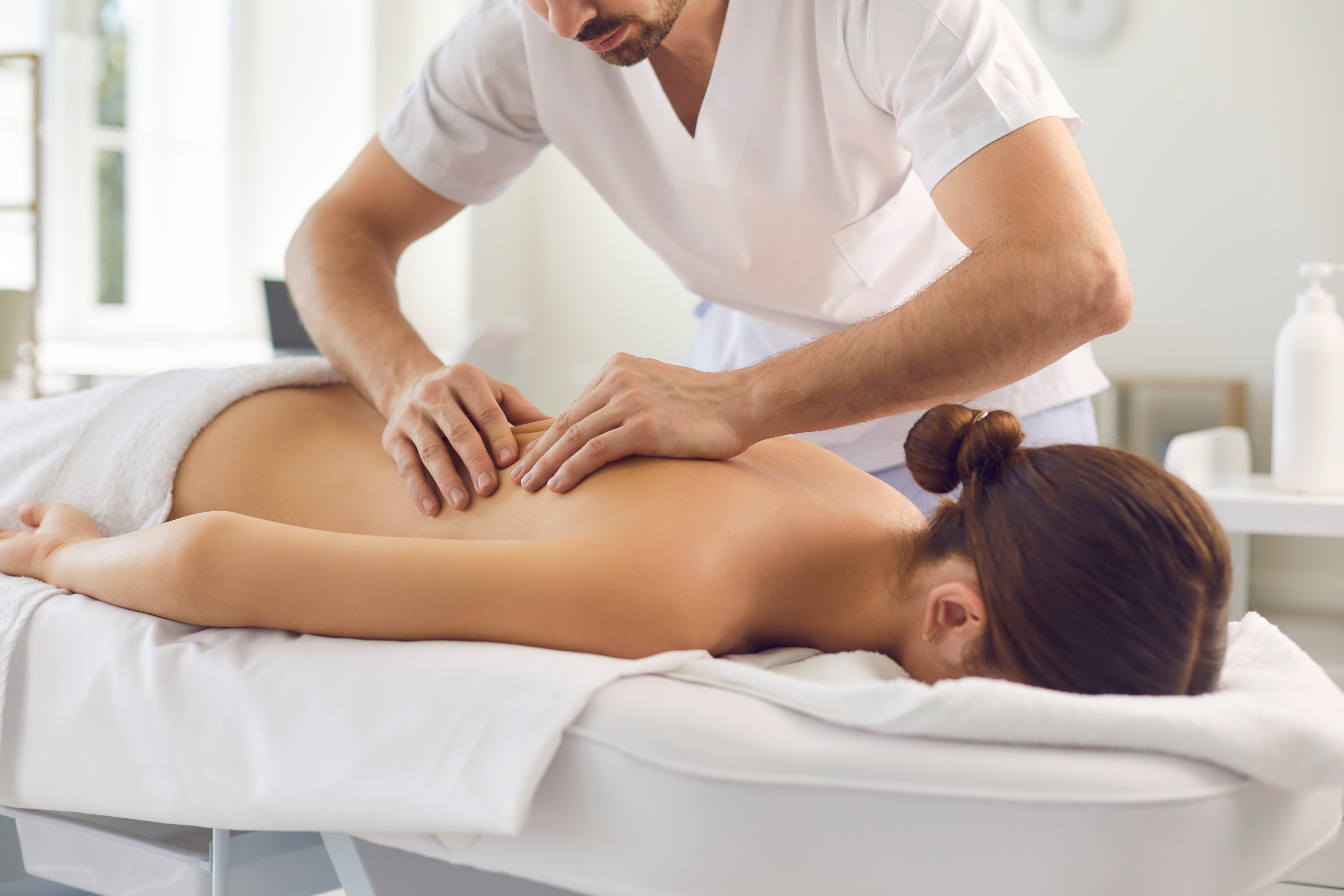 Woman Patient Getting Back Massage Procedure from Professional Chiropractor